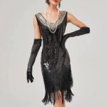 Photo d'une jeune femme portant une robe année 20 noire style Gatsby art déco à paillettes et franges, de longs gants en satin noir et un serre-tête à plumes, le tout sur un fond gris