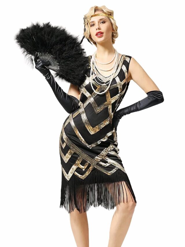 Photo d'une jeune femme blonde portant une robe années 20 noire sans manches à paillettes dorées formant des motifs entrecroisés, des franges au bas de la robe, elle porte de longs gants noirs satinés et un éventail de plumes noir dans la main, le tout sur un fond blanc