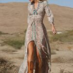 Photo d'une femme portant une robe bohème à motif avec une fente devant et des bottes de cow-boy, marchant dans le désert.