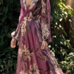 Robe bohème chic en mousseline violette à fleurs, portée par une femme devant des feuillages.