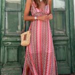 Photo d'une femme portant une Robe bohème rose longue à motifs avec un sac en paille, devant une porte verte.