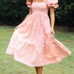 Photo d'une femme portant une robe bridgerton à carreaux, rouge sur de la pelouse.
