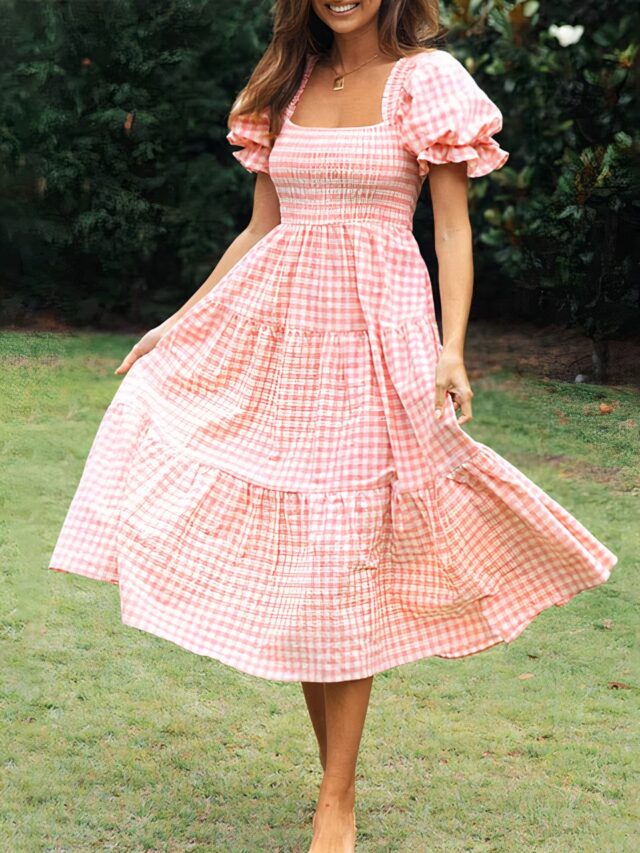 Photo d'une femme portant une robe bridgerton à carreaux, rouge sur de la pelouse.