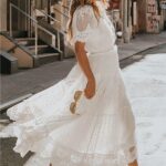 Photo d'une femme portant une robe champêtre en dentelle blanche, marchant dans la rue.