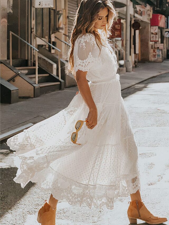 Photo d'une femme portant une robe champêtre en dentelle blanche, marchant dans la rue.