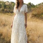 Photo d'une femme portant une robe blanche de style champêtre en mousseline fleurie dans un champs.