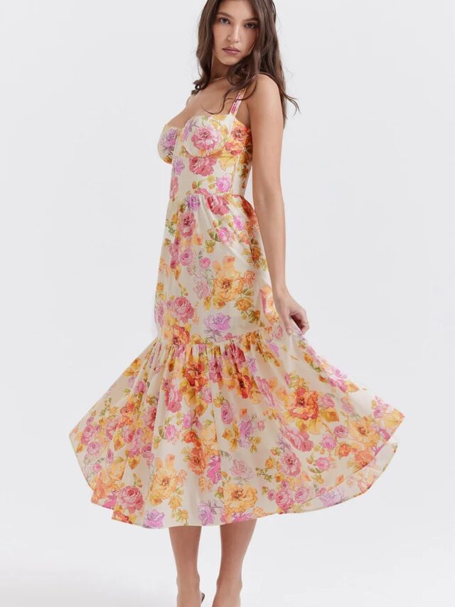 Robe champêtre à fleur dans les tons orange longueur midi, portée par une femme la faisant tourner.