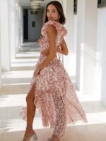 Photo d'une femme portant une robe champêtre fleurie élégante à découpes et fente rose dans un décor avec des colonnes.