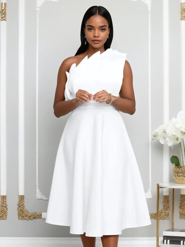 Femme portant une robe blanche asymétrique avec un buste plissé dans un décor chic.