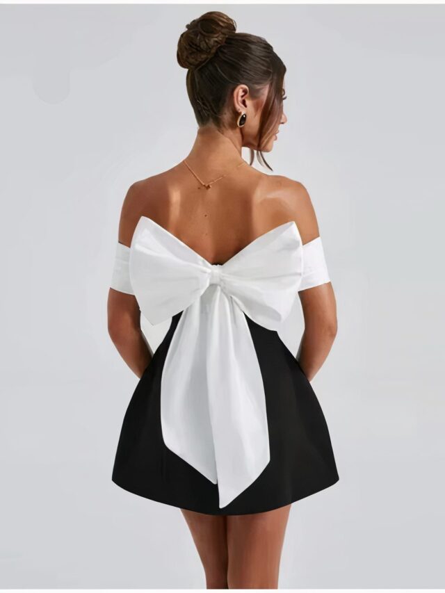 Femme portant une robe noire avec un nœud blanc.