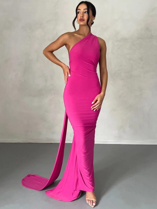 Photo d'une robe dos-nu rose de forme très ajustée portée par une jeune femme brune sur un fond beige et gris