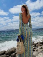 Photo d'une femme portant une robe dos nu longue bleu et jaune au crochet devant la mer