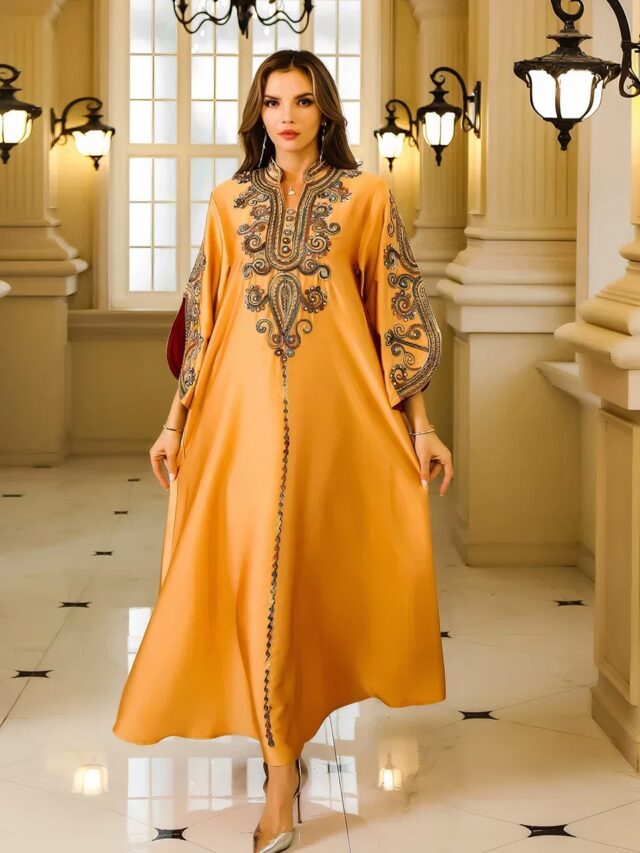 Photo d'une femme portant une robe kabyle orange brodée de soirée et marchant dans un couloir de palace