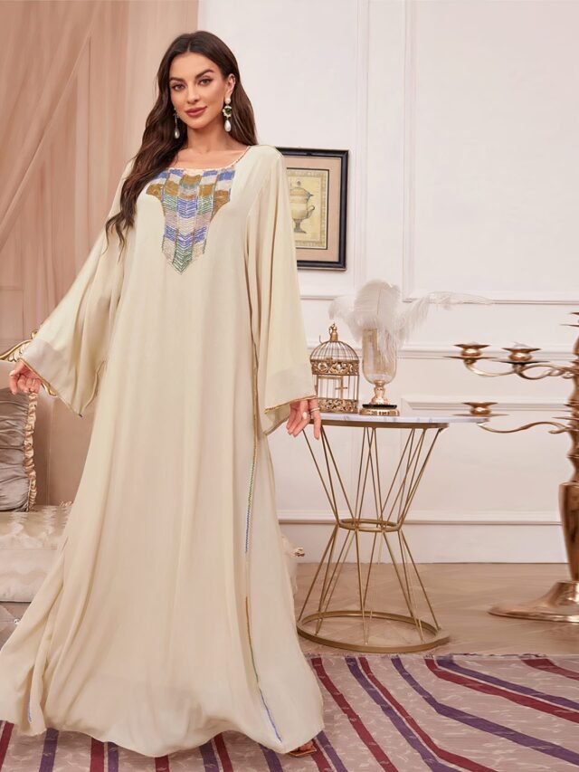 Photo d'une femme portant une robe kabyle beige de soirée,élégante devant perlé en couleurs dans un salon