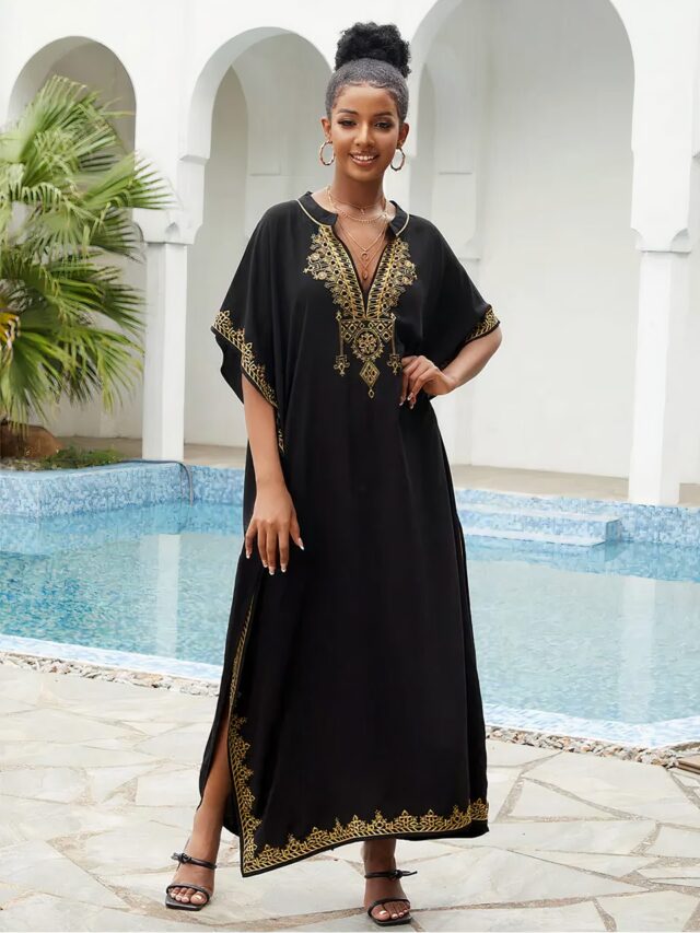 Photo d'une robe kabyle style caftan noire brodée dorée portée par une jeune femme au bord d'une piscine