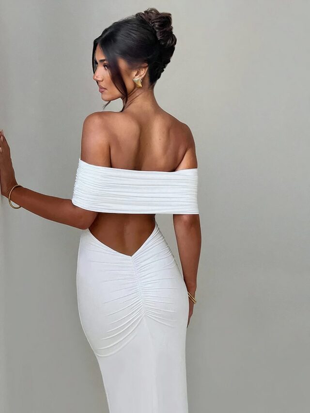 Photo d'une robe longue blanche dos nu à large bande portée par une jeune femme brune sur un fond gris