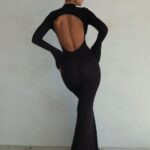 Photo d'une femme portant une robe dos-nu rond longue manches longues noire sur un fond gris