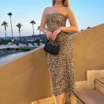 Femme portant une robe léopard bustier et se trouvant sur un escalier.