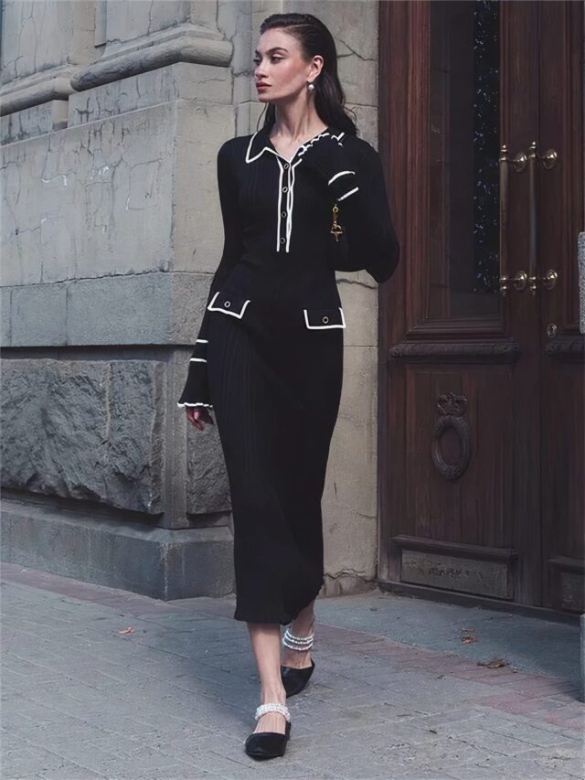 Photo d'une robe vintage longue noire en tricot à volants blancs portée par une jeune femme devant un porche