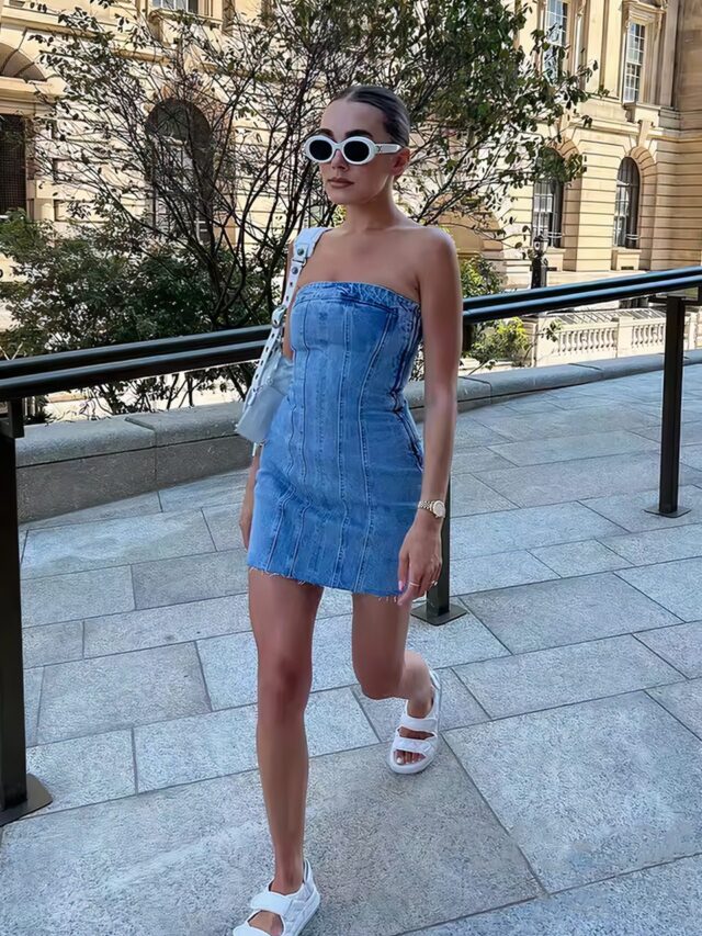 Photo d'une jeune femme marchant dans la rue et portant une rmini robe en jean vintage style 90's